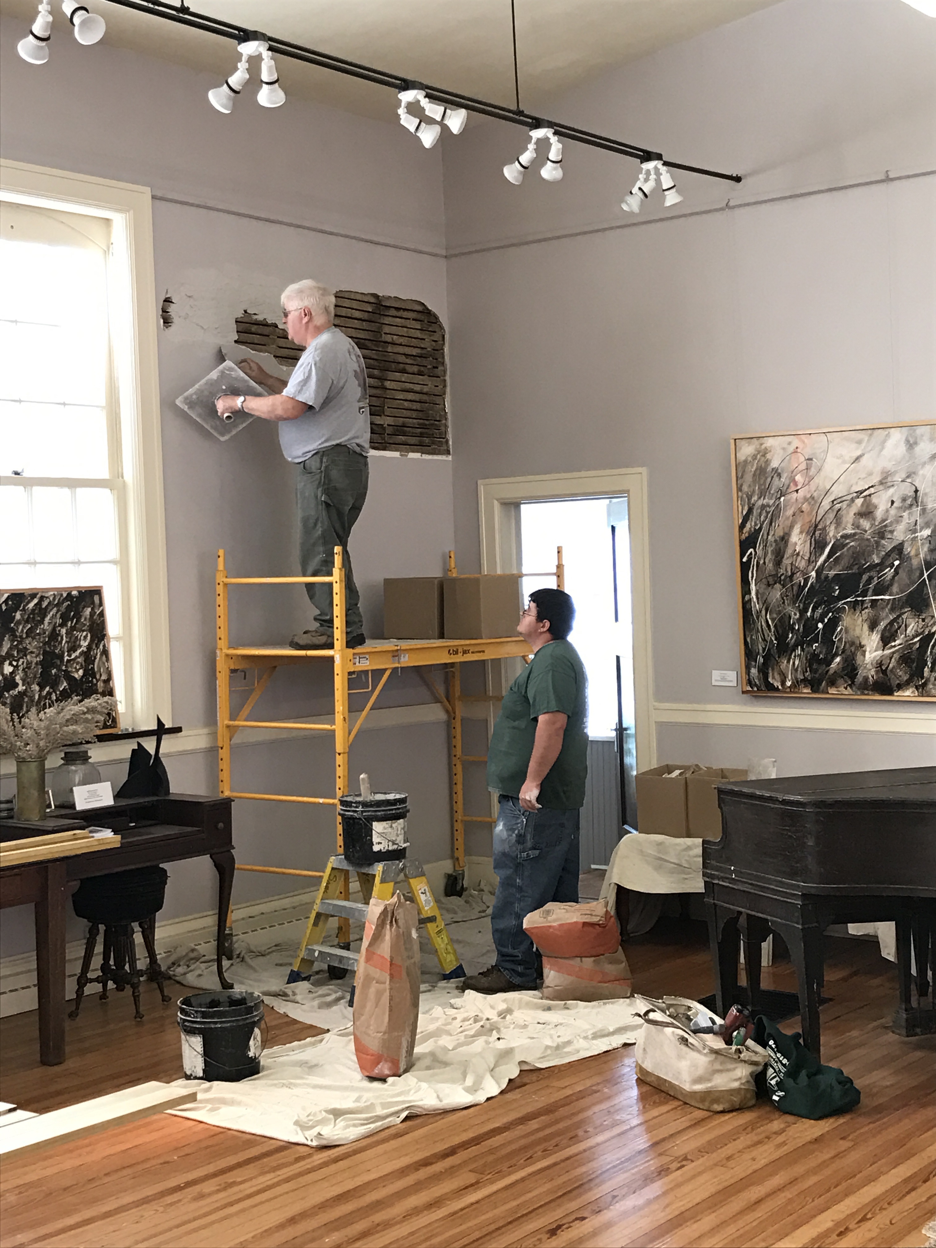 Workers plastering interior wall in furnished room