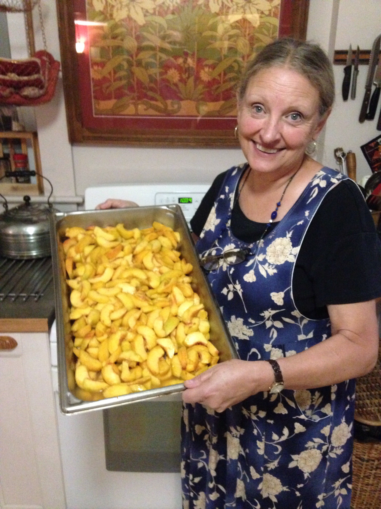 Smiling woman holding tray of sliced peaches