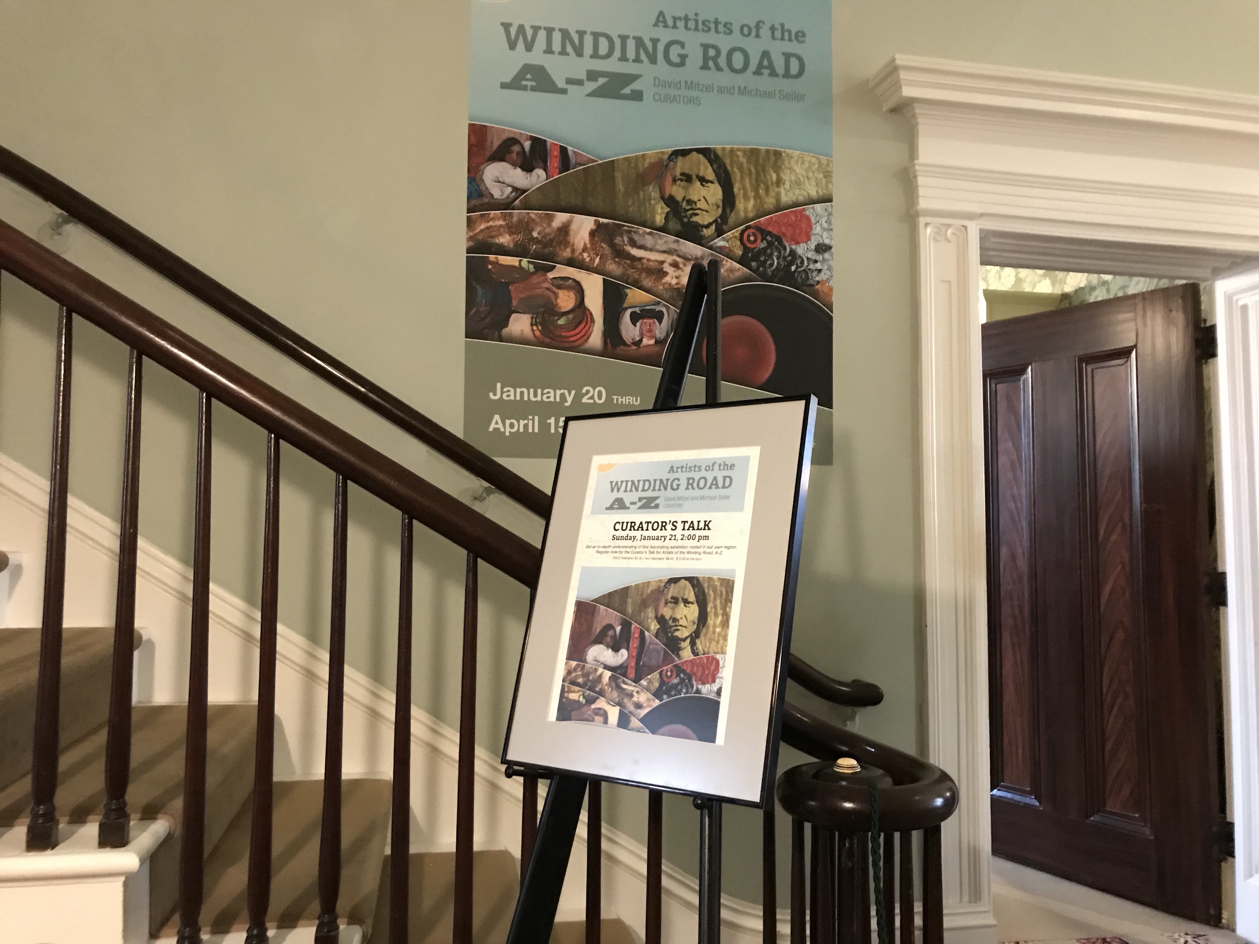 Exhibit posters and framed sign by staircase