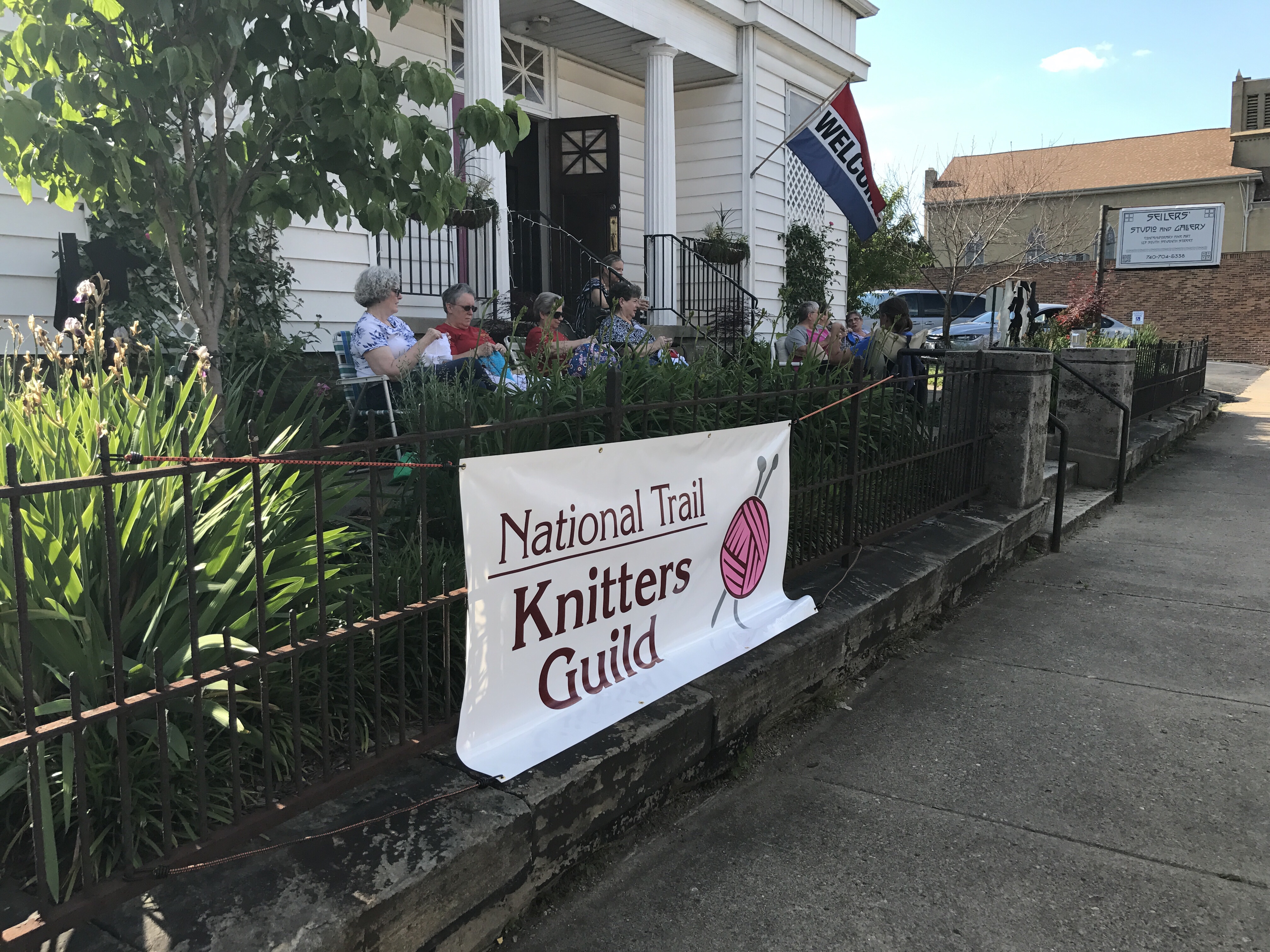 Knitting group on porch with guild banner