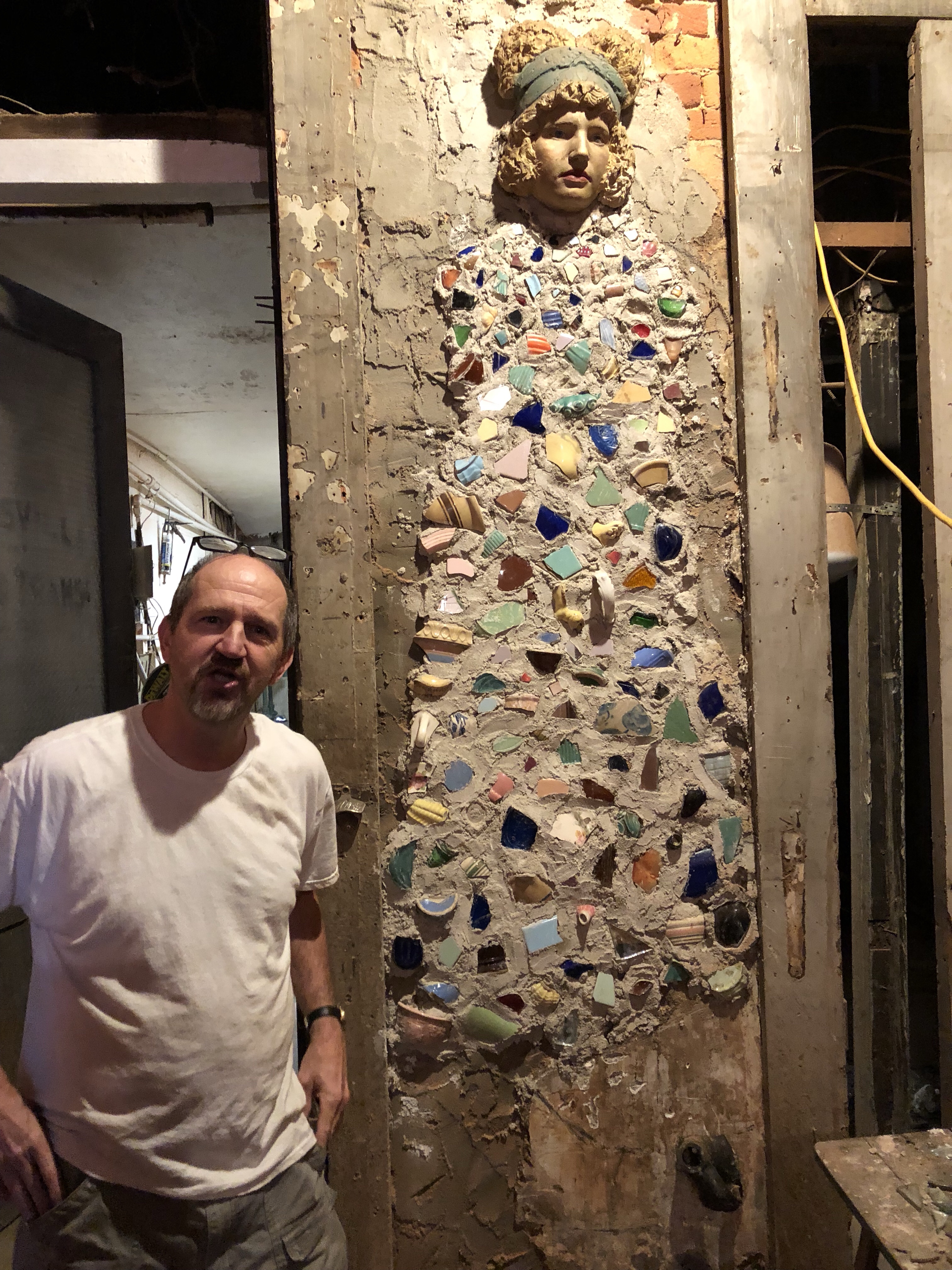 Man beside mosaic-embedded sculpted female figure