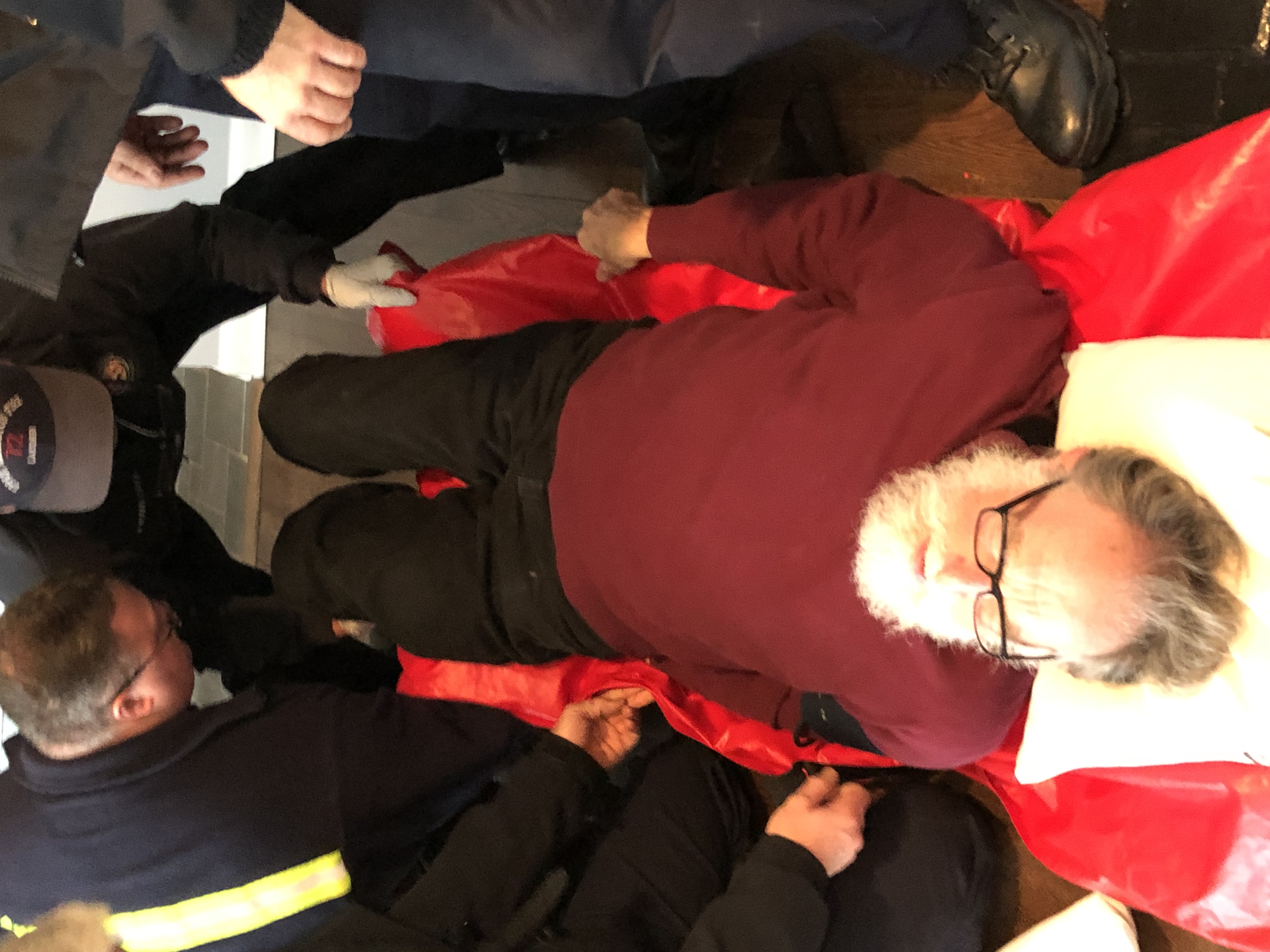 Bearded man on red stretcher assisted by responders