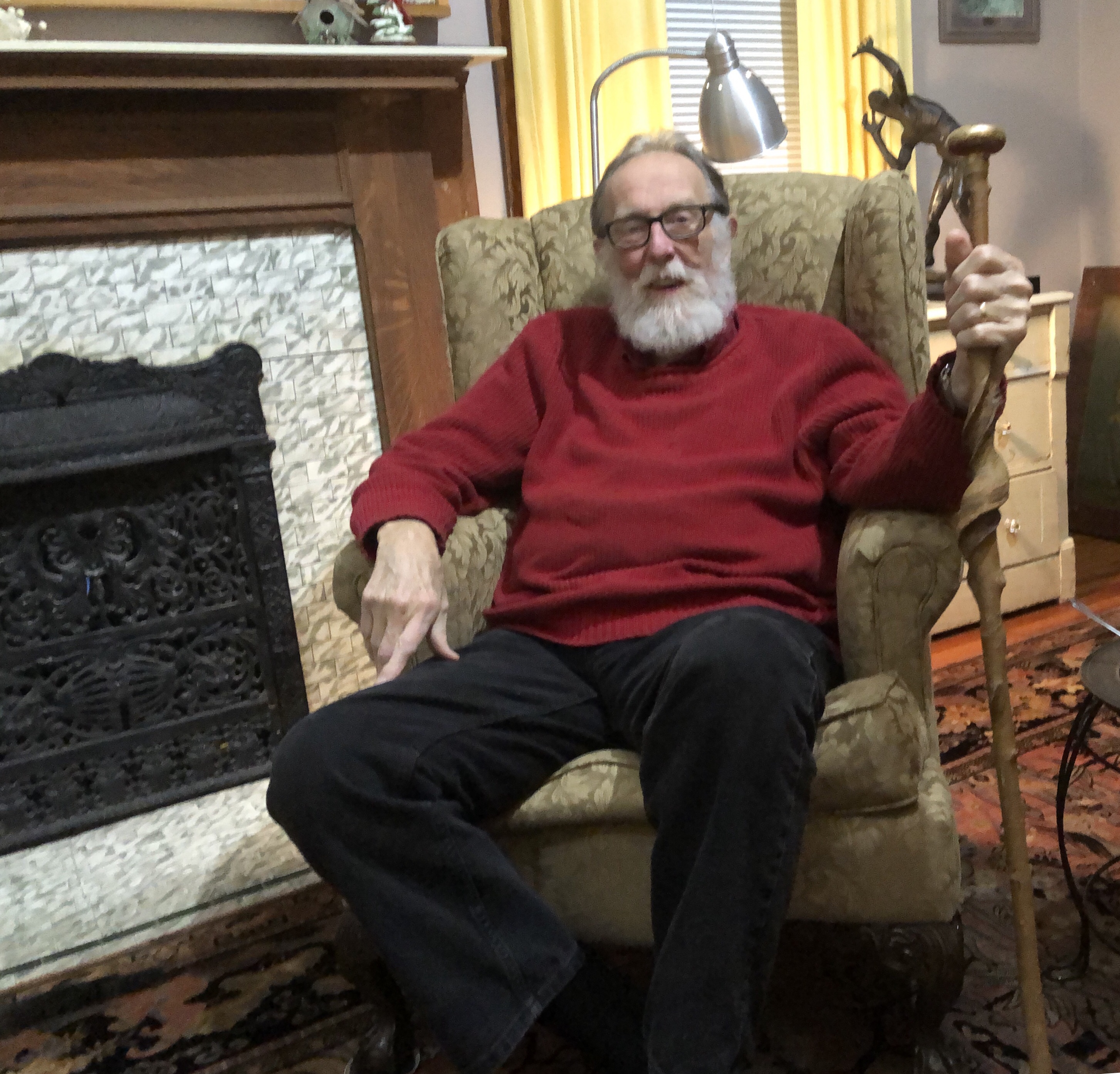 Bearded man with cane sitting in armchair