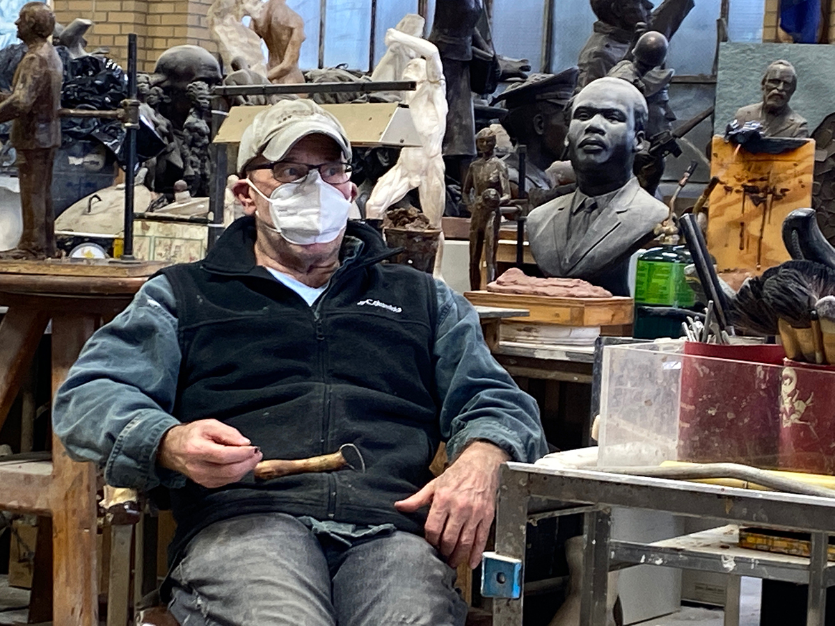 Person wearing mask sitting in sculpture studio