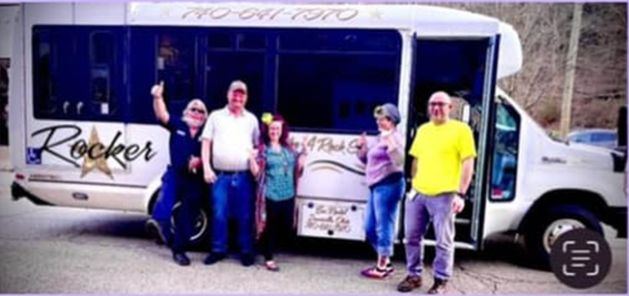 People posing in front of white shuttle bus